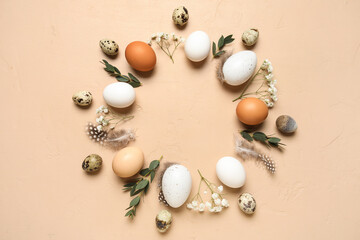 Frame made from Easter eggs, feathers, leaves and flowers on beige grunge background