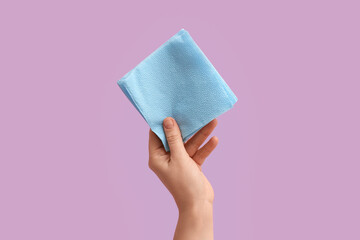 Female hand with blue paper napkins on lilac background