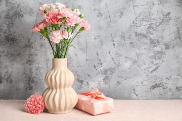 Vase with bouquet of different beautiful flowers and gift box on white table. Mother's Day celebration