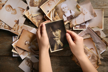 Female hands with old photos of relatives on wooden background. Concept of family tree