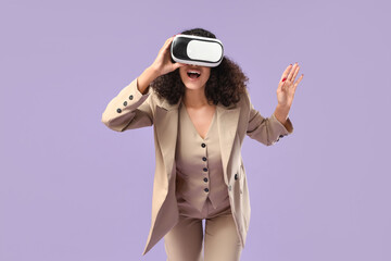 Naklejka premium Young African-American businesswoman with VR glasses on lilac background