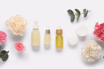 Different cosmetics and beautiful flowers on light background