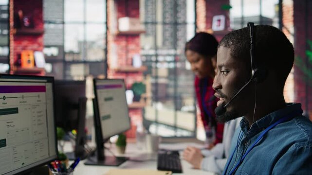 Diverse customer center workers assisting clients with installing software. Multiethnic team of call center agents using remote access tools to connect to customer devices, fixing errors, camera B