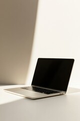 Laptop on minimalist desk in sunlit workspace offering modern elegance and simplicity