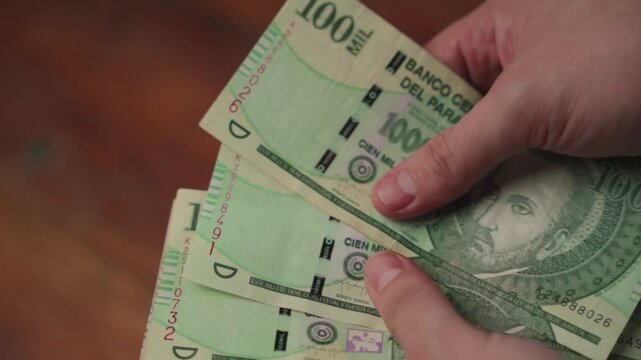 Close-up of a man's hands counting Paraguayan guaran&iacute; bills