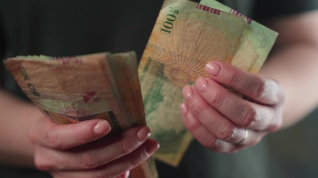 Close-up of a woman's hands counting Paraguayan currency bills