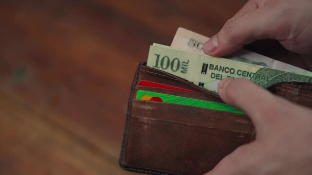 Hands taking Paraguayan currency bills out of a wallet