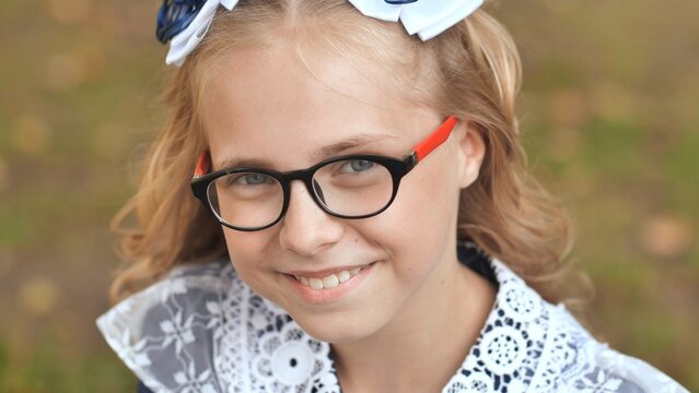 Portrait of a smiling 13 year old girl put on glasses. Face close up.