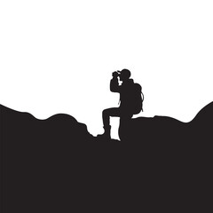Silhouette of a hiker with a backpack looking through binoculars on a mountain