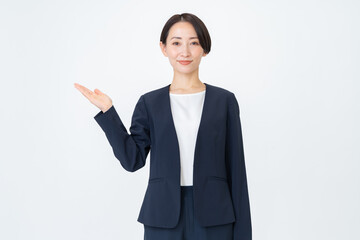 白背景で案内をするスーツを着た女性