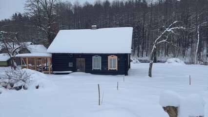 Traditional wooden cottage covered by snow during winter in Latvia