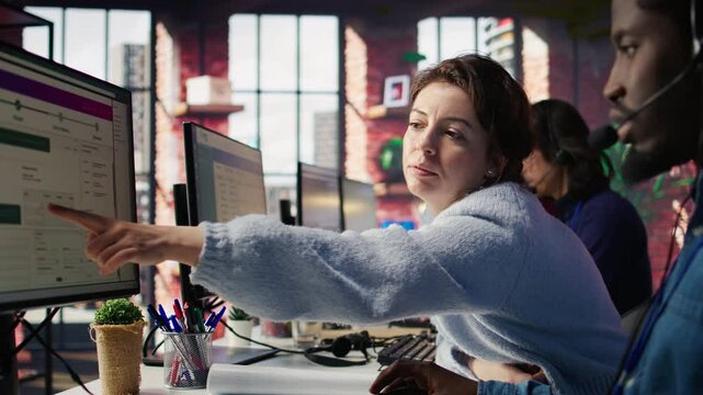 Call center onboarding employee providing training to new agent recruit on technical PC tools. Manager in customer support department office providing support on how to use company platforms, camera B