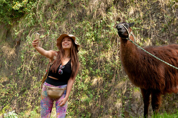 A woman enthusiastically taking a selfie with a llama while surrounded by beautiful nature © Martin Stock Studio