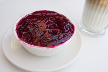 Delicious berry compote served with a creamy drink on a white table