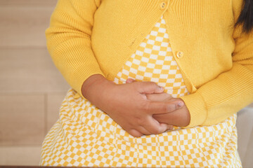 Child suffering stomach pain sitting on sofa 