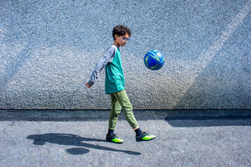Young boy juggling soccer ball against wall © Brand