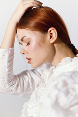 Thoughtful young woman with red hair wearing a white blouse, expressing contemplation in a...