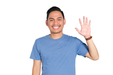 Smiling young Asian man waving hello with raised hand, wearing blue t-shirt, isolated on transparent background