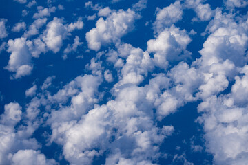 Blue sky with fluffy clouds background. Bright blue sky background. Cloudscape with white clouds. Calm sky on a sunny day. Sunlight through the clouds wallpaper. Spring sky with soft clouds.