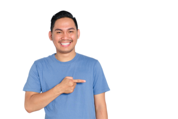 Smiling young Asian man in blue shirt pointing to the side with finger, looking happy and friendly, isolated on transparent background