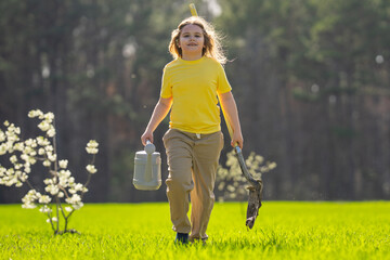 Child growing a tree in garden. Child digging soil with shovel and planting tree. Child gardener...