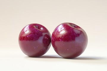 Two ripe, red plums sit side-by-side on a white background.