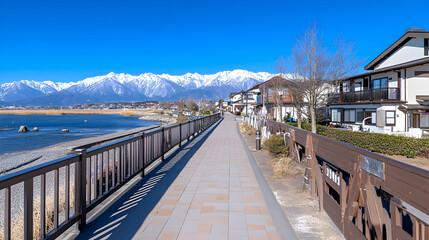 Scenic lakeside promenade with snow-capped mountains in the background on a sunny day