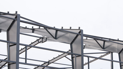 Metal construction, in the photo the structure of the building frame made of metal beams against the background of a gray sky