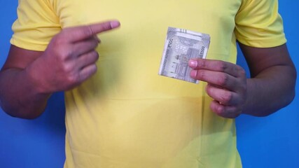 Man holding money on his one hand and pointing towards currency from other hand. - Powered by Adobe