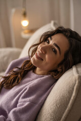Serene woman relaxing on sofa, enjoying peaceful moment at home