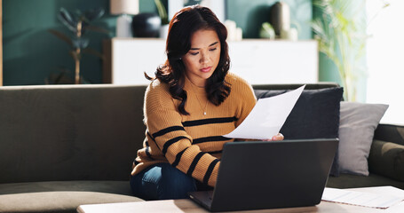 Asian woman, laptop and sofa with documents for finance, budget planning or debt review at home....