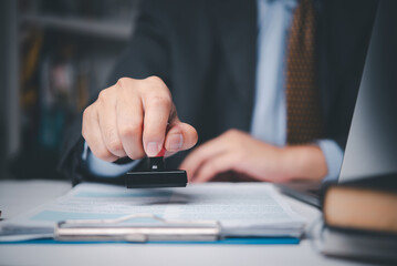 Businessman stamping contract document on desk, symbolizing legal approval, corporate agreement,...