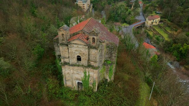 Abandoned church, Santa Maria di Lago Pigo, Nostra Signora di Nogareto or Madonna dell&rsquo;Assunta surrounded by dense vegetation. Aerial top-down orbiting