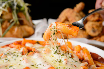 Lifting the rice cake of Cheese Tteokbokki with a fork to show the cheese stretching
