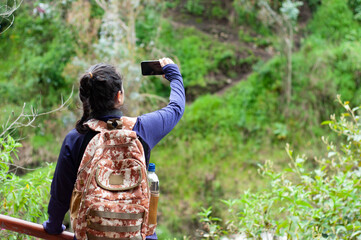 A Hiker Enthusiastically Taking a Photo Amidst the Lush Green Nature Surroundings