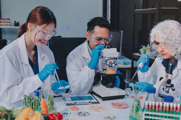 Team Asian scientists in a lab conducting food research using a microscope and lab equipment,...