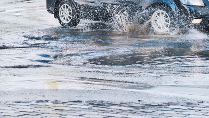 High speed vehicle splashing water while driving through roadside puddle, generating dramatic spray...