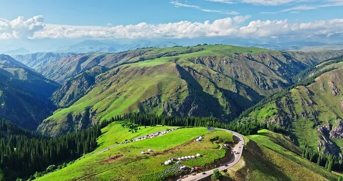 Aerial view of a winding road and green grassland with mountain natural landscape in Xinjiang. Duku highway is the most beautiful highway in China.