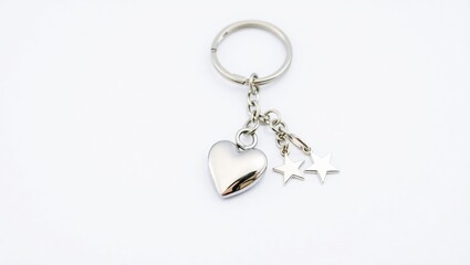 Shiny silver keychain with heart and star charms. Metal chain connects charms to keyring. Simple white background. Stylish accessory. Perfect gift for someone special.