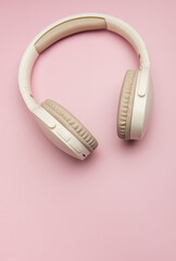 Modern wireless headphones lying on pink background