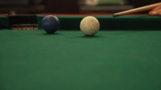 Slow motion shot of cue striking pool ball on green table