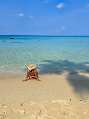 A tranquil day on Koh Kood Island, Thailand, where gentle waves lap at the shore. A child plays in the crystal-clear waters, embraced by the warm sun and breathtaking landscape.