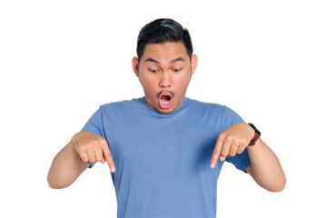 Surprised young Asian man pointing down with both hands, wearing casual blue t-shirt, isolated on transparent background