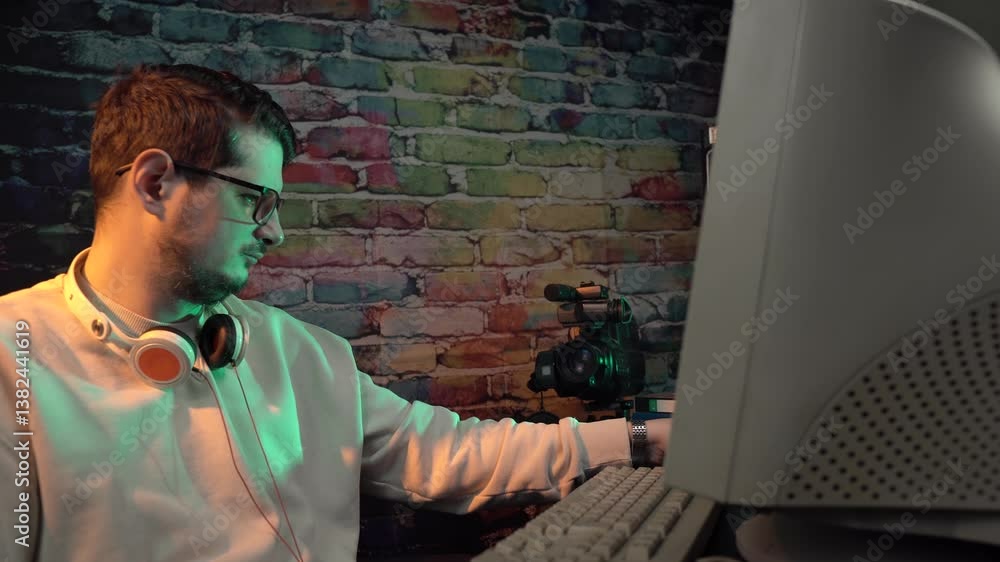 Aufkleber video editor from 1990's in front of desktop computer placing vhs cassette tape into vcr