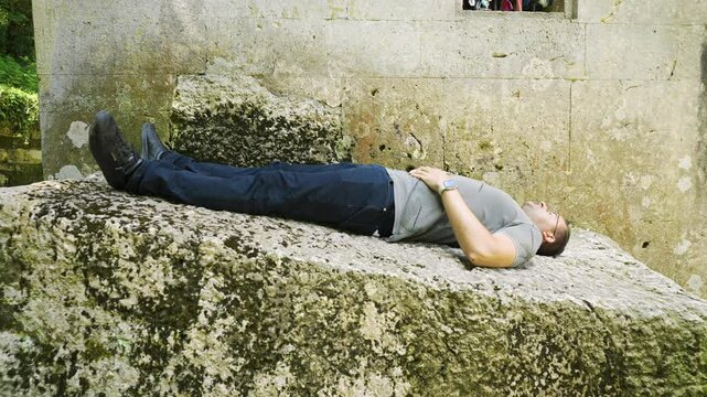 A lone tourist lying on a boulder in front of the mausoleum of the Alevian and Islamic saint Demir Baba Teke, located in the municipality of Isperih, Razgrad province in Bulgaria.