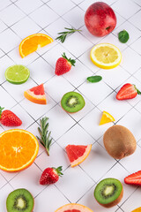 Fresh fruits like strawberries, citrus, kiwi and apple on white background with grid pattern. Vibrant and minimalist composition. Concept of healthy eating and freshness