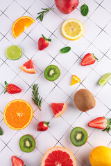 Top view of slices of citrus fruits, strawberries and kiwi arranged in a harmonious design on geometric background. Concept of balanced diet and vitamins