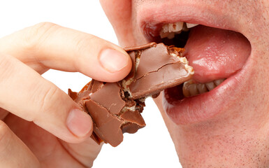 A man is eating a chocolate bar with his mouth open