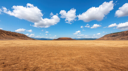 Obraz premium Extinct Volcano Heritage Theme, Ancient volcanic terrain with dry grassland under blue sky and clouds