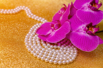 A branch of purple orchids on a shiny gold background
